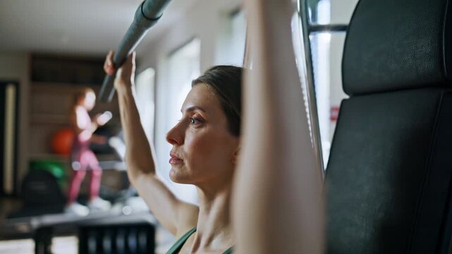 Woman performing lat pulldown in gym closeup. Portrait athlete training hands