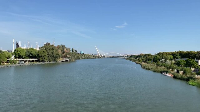 a Long view down the Guadalquivir shows rowers training as Barqueta and Alamillo bridges frame the distant skyline