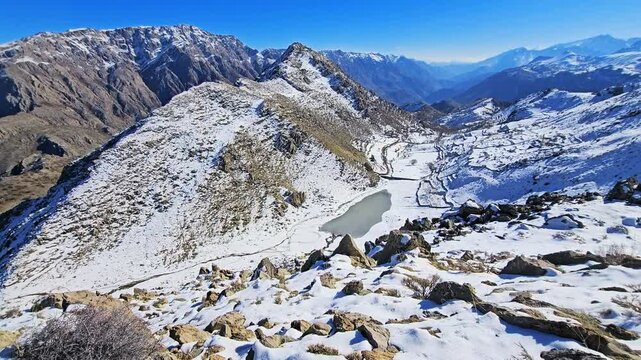 Snow-covered mountain valley featuring a seasonal wetland basin between rocky slopes under a clear blue sky, quiet winter landscape with natural formations and open space.
📍SarPir, Hawraman Takht
