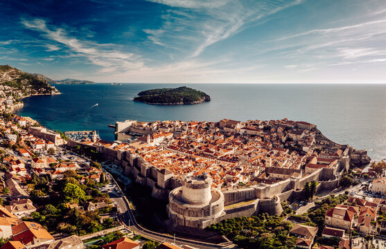 Aerial view of the ancient walled city, a tapestry of terracotta roofs cascading towards the shimmering Adriatic, framed by the rugged coastline, Dubrovnik, Dubrovnik-Neretva County, Croatia.