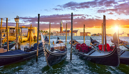 Venice, Italy. View at San Giorgio Maggiore from the Marco Square with Venetian gondolas moored by pear floating on water of Grand Canal. Scenic sunset in venice city.. © Yasonya