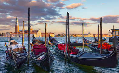 Venice, Italy. View at San Giorgio Maggiore from the Marco Square with Venetian gondolas moored by pear floating on water of Grand Canal. Scenic sunset in venice city.. © Yasonya