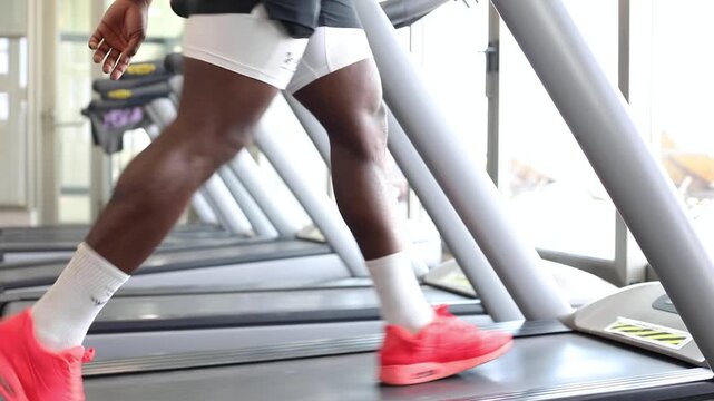 Legs walking on treadmill during gym warm-up. Close-up view of legs walking on a treadmill during warm-up in a gym, showing fitness preparation, movement, and indoor cardio training.
