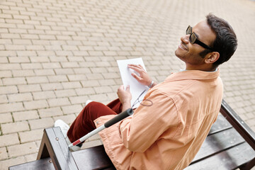 Handsome Indian blind man enjoys a sunny day while sketching on a park bench