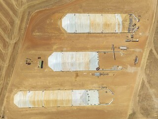 Aerial view of agricultural storage facilities casting shadows on the arid land, creating a geometric pattern of light and shade, Caledon, Western Cape, South Africa.