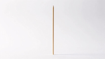 A slender wooden skewer stands vertically isolated against a clean white background, highlighting its smooth bamboo texture and sharp, pointed tip.