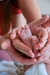 New parents hands gently cradling tiny newborn feet, symbolizing love, protection, and the precious bond within a family, valuing childhood and new beginnings