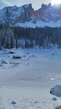 Escursionista Solitario sul Lago di Carezza Ghiacciato - Panorama Dolomiti