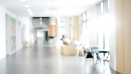 Blurry modern office lobby corridor with seating area and bright natural light