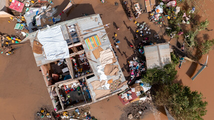 Aerial view of homes submerged in muddy floodwaters, their roofs barely visible amidst scattered debris and displaced belongings, Buzi, Sofala Province, Mozambique.