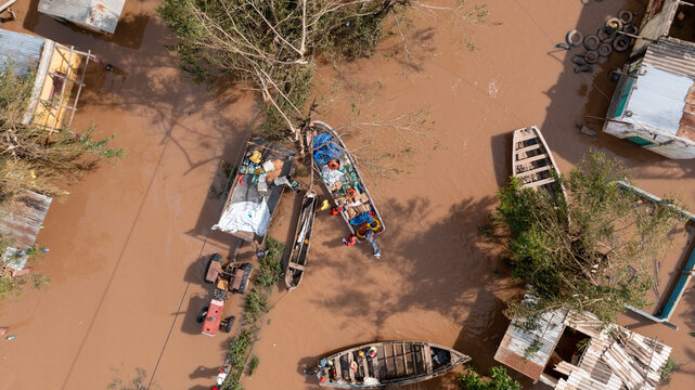 Aerial view of boats amidst the floodwaters reflecting the sky, homes submerged, and trees struggling against the current, Beira, Sofala Province, Mozambique.