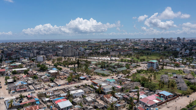 Aerial view of corrugated iron roofs shimmering under the sun, contrasting with the city's skyline reaching towards the horizon, Beira, Sofala Province, Mozambique.
