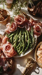 Green beans with italian prosciutto roses and fresh rosemary on ceramic plate, surrounded by artisan bread and flowers in warm sunlight on festive table, romantic rustic dinner concept