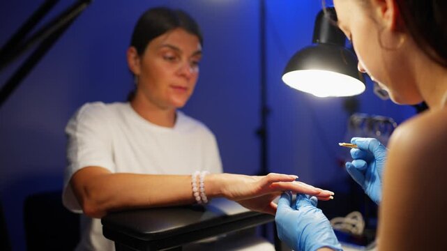 The client explains to the artist exactly what kind of coating and shape of her nails she wants. High quality 4k footage