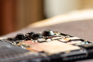 A macro shot of a smartphone's exposed circuit board highlighting its multi-lens camera module and surrounding electronic components on a blurred background.