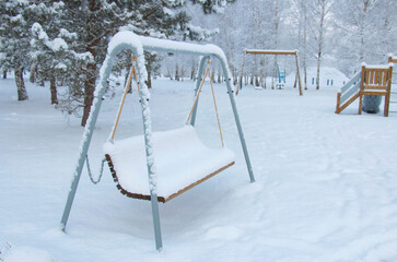 children's eco playground, children's swing covered with a snowdrift.