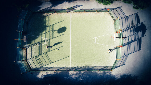 Aerial view of a sports field with long shadows cast across the green court, Narbonne, France.