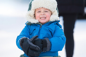 Little Boy with Cheesy Smile Bundled Up Outside on a Snowy Day