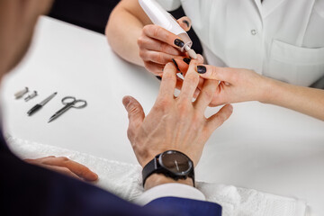 Manicure master working with male client in beauty salon. Man nail care