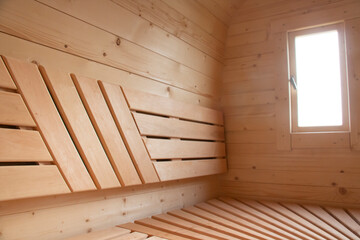 Light, spacious sauna made of natural wood with a heater.
