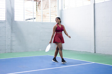 Female paddle tennis player walking on indoor court after match