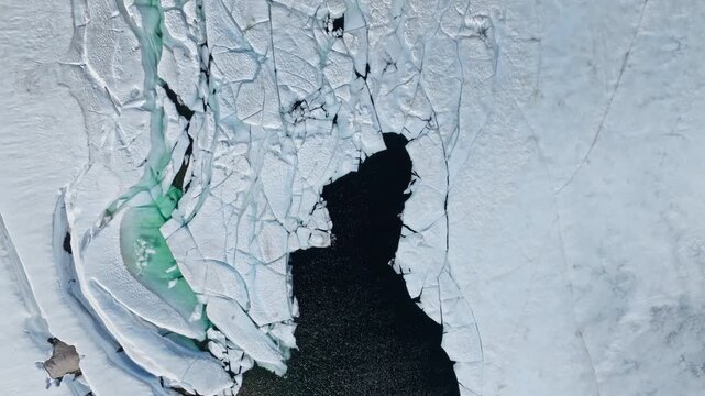 Top-down drone view of cracked lake ice on Hardangervidda National Park. Abstract natural patterns form as ice breaks apart during seasonal thaw.