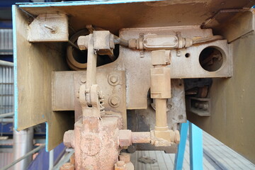 Close-up view of industrial machinery components, featuring pipes, valves, and mechanical linkages within a blue metallic structure