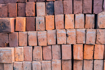 Pila ordenada de ladrillos de arcilla con textura áspera y tonos cálidos para construcción
