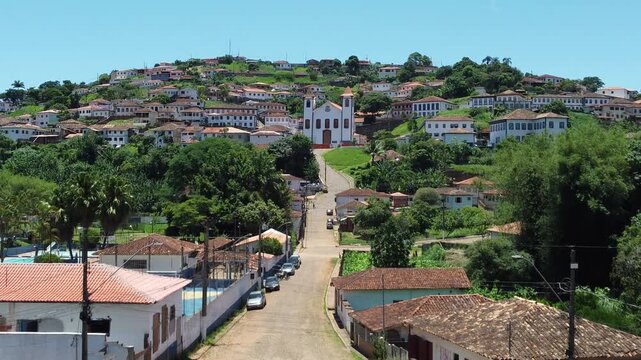 Drone video over the historic city of Serro, Minas Gerais, Brazil, highlighting the Matriz Church and colonial architecture surrounded by mountains, preserving Brazilian heritage and baroque history.