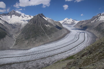 Aerial view of winding glacier in alpine mountain valley on clear day