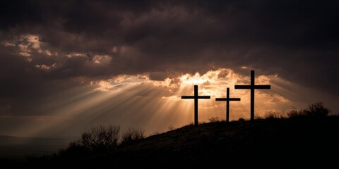 Three crosses on a hill at sunset with divine light rays through dark storm clouds