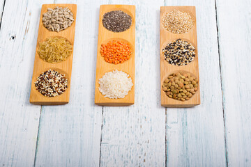 gluten free grains, seeds on bamboo plate, white wood table