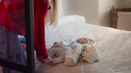 Kind babysitter playing with happy newborn baby on bed, child care concept