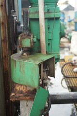 Close-up view of an industrial machinery motor with green casing and visible rust and metal parts