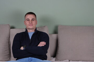portrait of a young businessman sitting on sofa, professional man relaxing on couch, copy space background