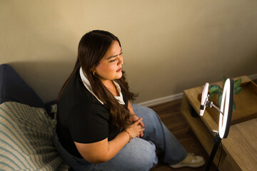 Content creator woman streaming live video to social media from home. She is making a vlog or recording