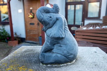 Small elephant statue on concrete base outdoors