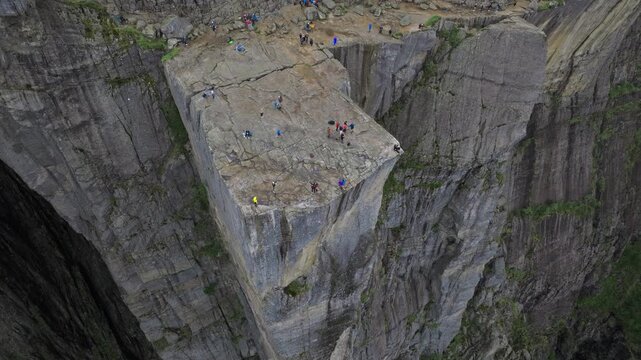 Tourists standing on Pulpit Rock Preikestolen Norway. People gather on the flat rock plateau, taking photos and sightseeing at one of Norway&rsquo;s most iconic viewpoints.