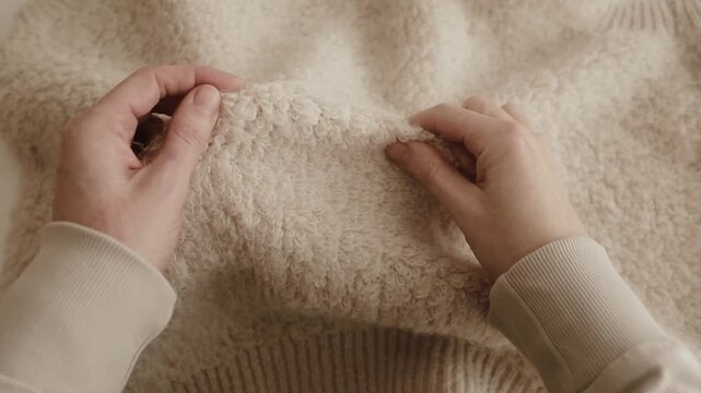 Closeup aesthetic video of hands touching soft wool sweater. Ivory fluffy knitted sweater for cold winter. Appreciating pleasant texture of high quality clothes. Soft and cosy clothes. 