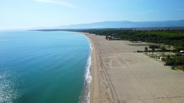 Aerial drone flying forward with a landscape view showing ocean on one side and beach on the other at Sibari beach Italy