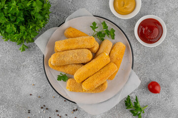 Crispy breaded mozzarella sticks on a plate with parsley, served with ketchup and mustard dips. Golden fried texture, appetizing snack on gray background