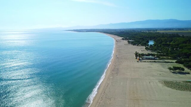 Aerial drone flying forward and descending over a coastal landscape with ocean on the left and beach on the right at Sibari beach Italy