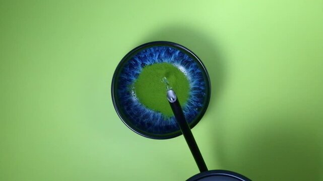 Leuchtend blaue Sch&uuml;ssel mit gr&uuml;nem Matcha-Pulver und hei&szlig;em Wasser