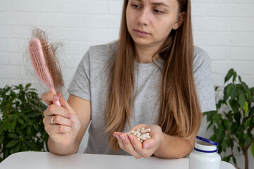 woman holding hairbrush with lost hair and a bottle of vitamins for baldness