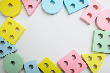Top view of assorted wooden shape sorter toys in pastel colors, arranged in a circle on a white...