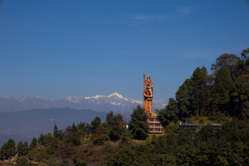 Kailashnath Mahadev statue at Sanga, Nepal, the world&rsquo;s tallest Lord Shiva statue, standing on a green hill with Himalayan mountains and clear blue sky. Ideal for uses like tourism promotion.