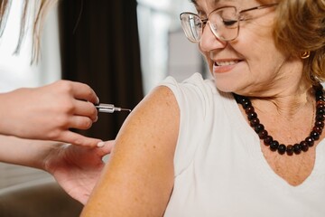Senior woman receiving flu vaccination, smiling