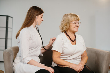 Doctor examining senior woman with stethoscope in clinic