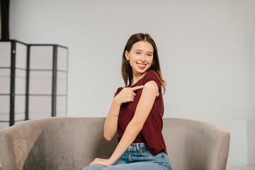 Smiling young woman showing arm after vaccination