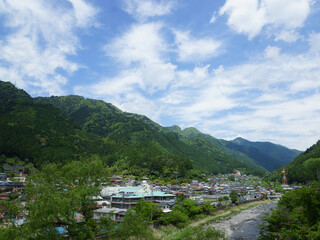 Obraz premium Rural Town and River Surrounded by Green Mountains in Japan